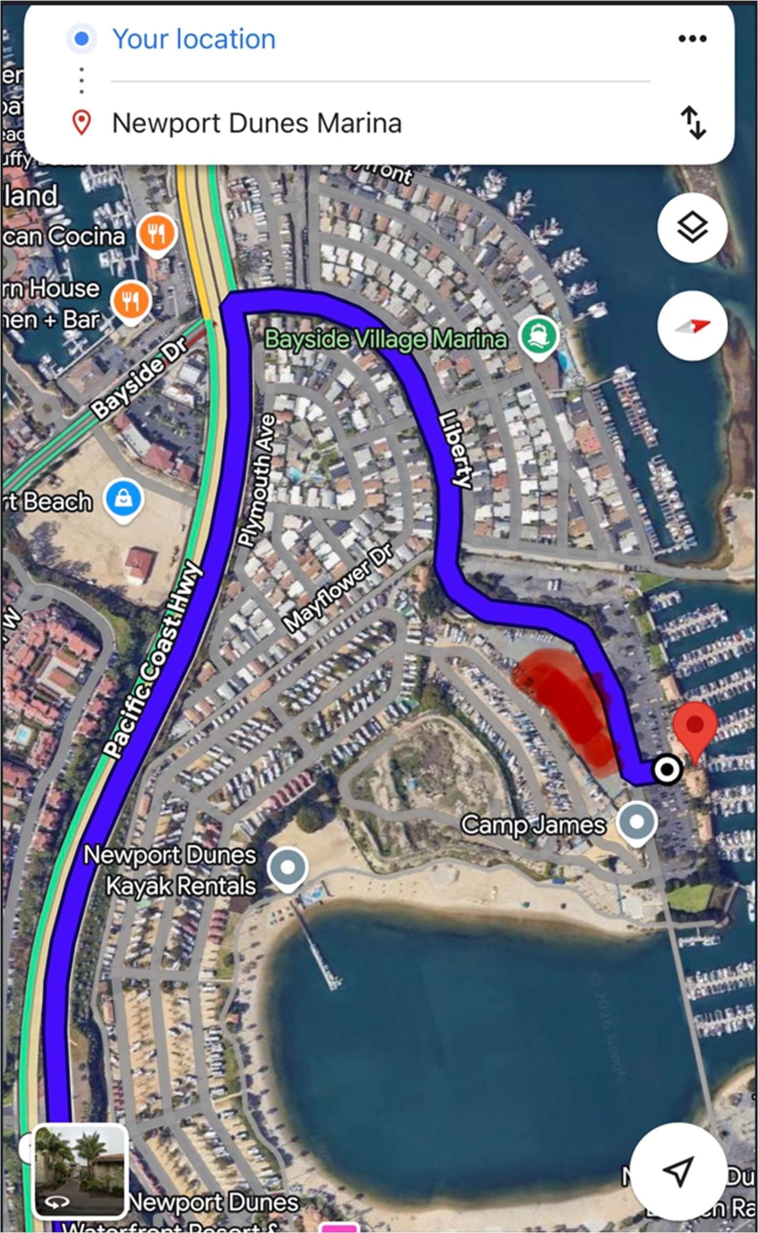 Driving route traced in blue from Pacific Coast Highway onto North Bayside Drive and along to the resort entrance, beside the gravel parking lot shaded red